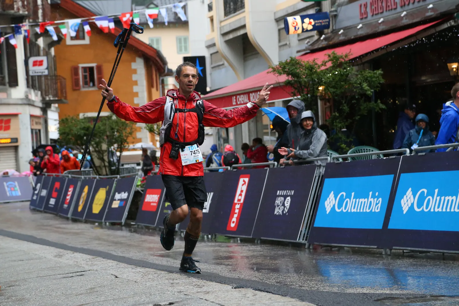 Coureur levant les bras dans les rues d’un village à l’arrivée.
